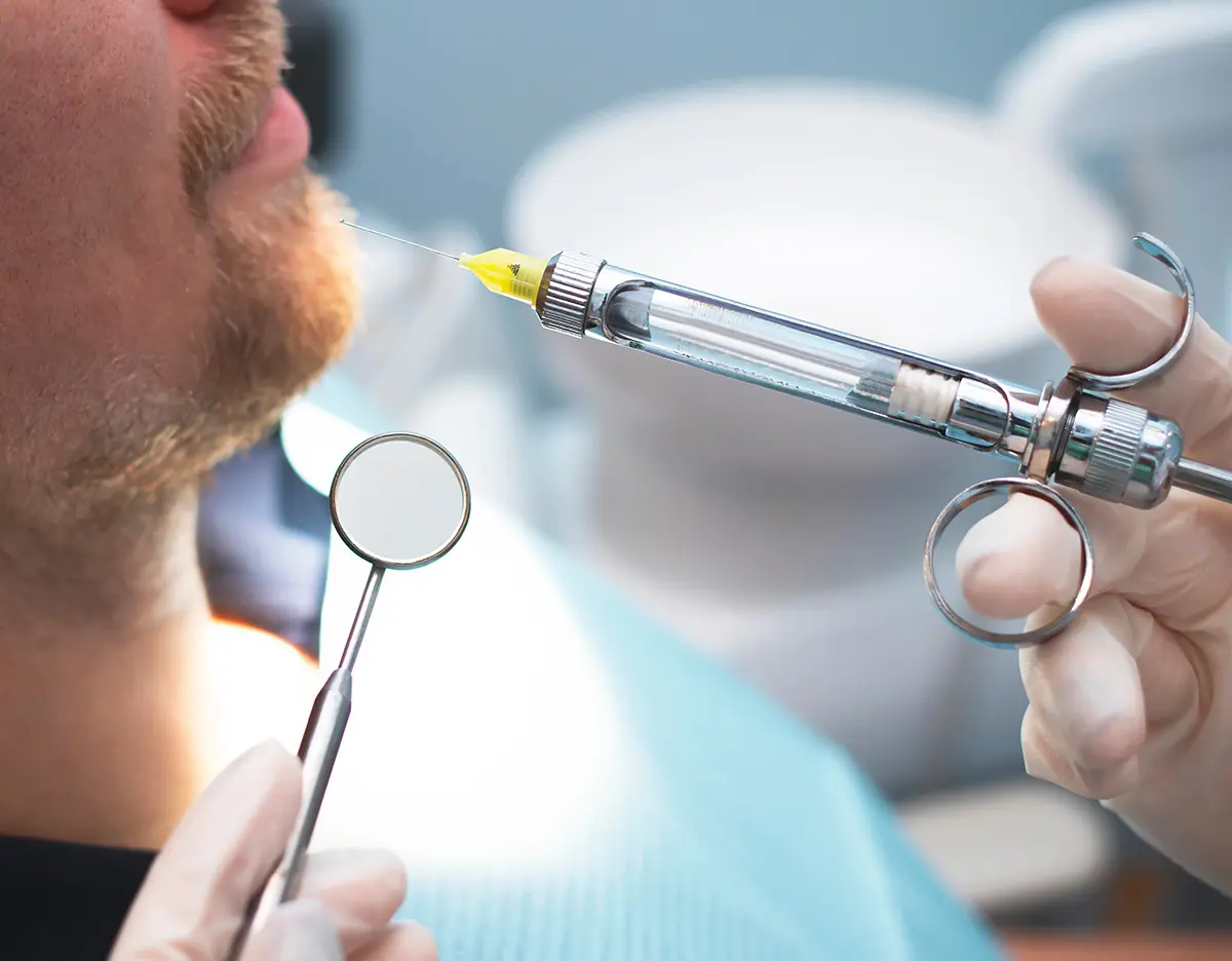Dentistry, somatology close-up hand makes anesthesia from a specialized metal syringe. Doctor Dentist making an injection of pain reliever.